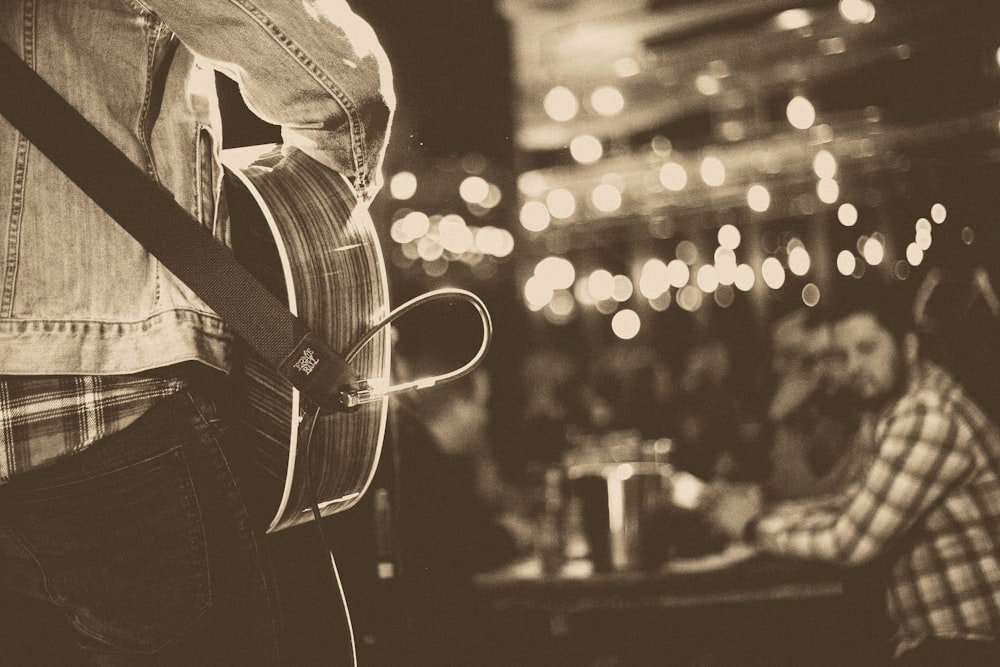 grayscale photo of person playing guitar on stage