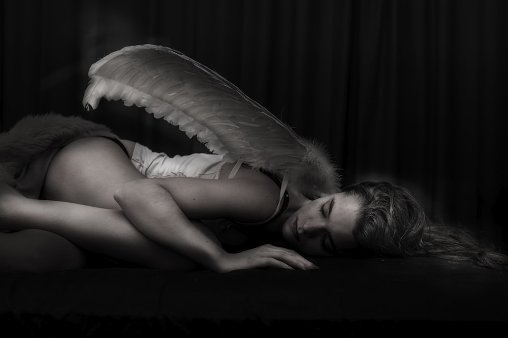 mulher com asa de anjo deitada no chão