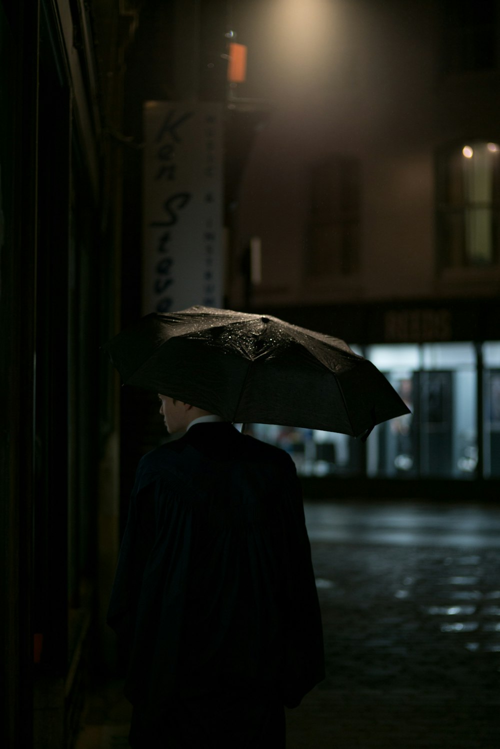 Mann in schwarzer Anzugjacke unter Regenschirm