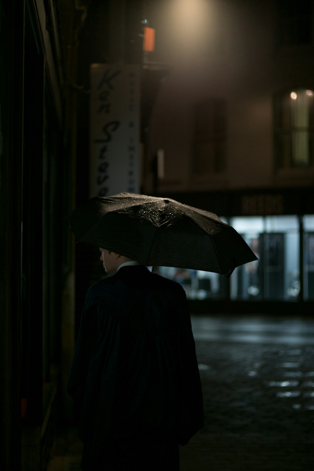 우산 아래 검은 양복 재킷을 입은 남자
