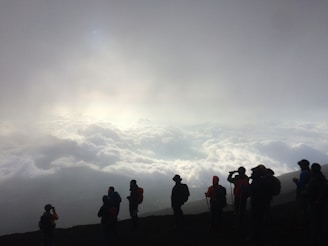 A panoramic view from a summit showing a small group silhouetted against the horizon, embodying connection and perspective.