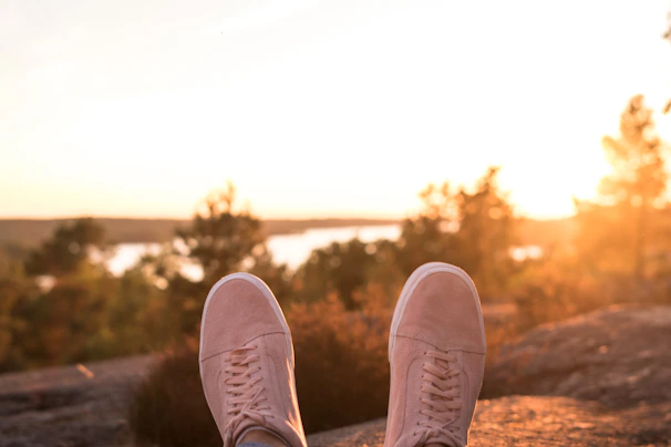 A pair of minimalistic sneakers resting on pavement beside a trendy backpack, bathed in warm afternoon light.