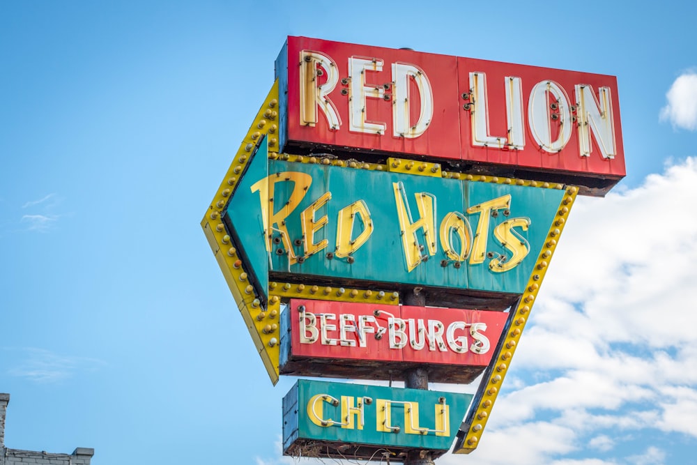 Signalisation Red Lion, Red Hots, Beef Burgs et Chili sous un ciel nuageux blanc et bleu