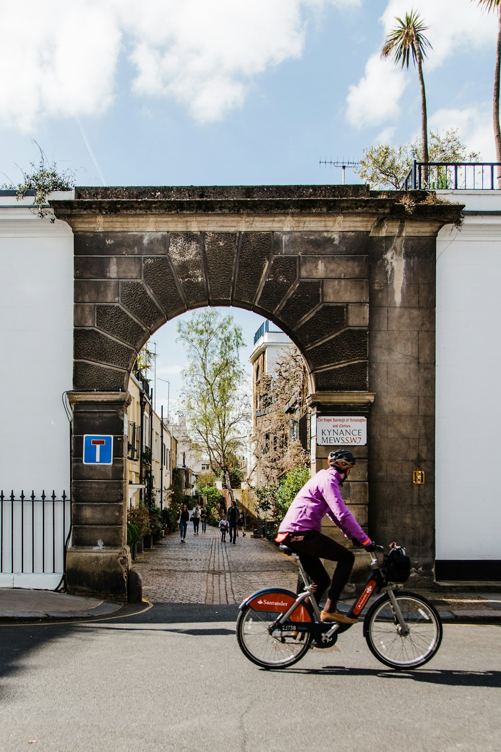 a person riding a bike in front of an arch
