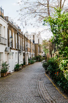 A cobblestone street in Kynance Mews, London, lined with white and brick houses