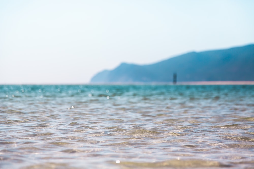 photo of clear body of water across mountain