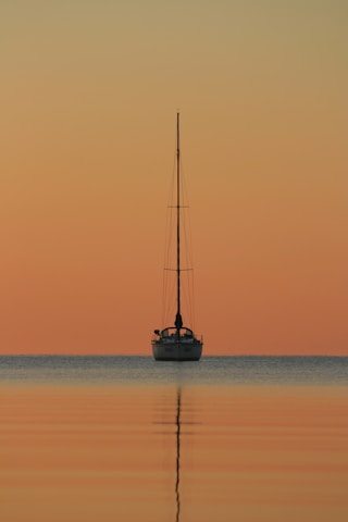white and black boat on body of water during golden hour
