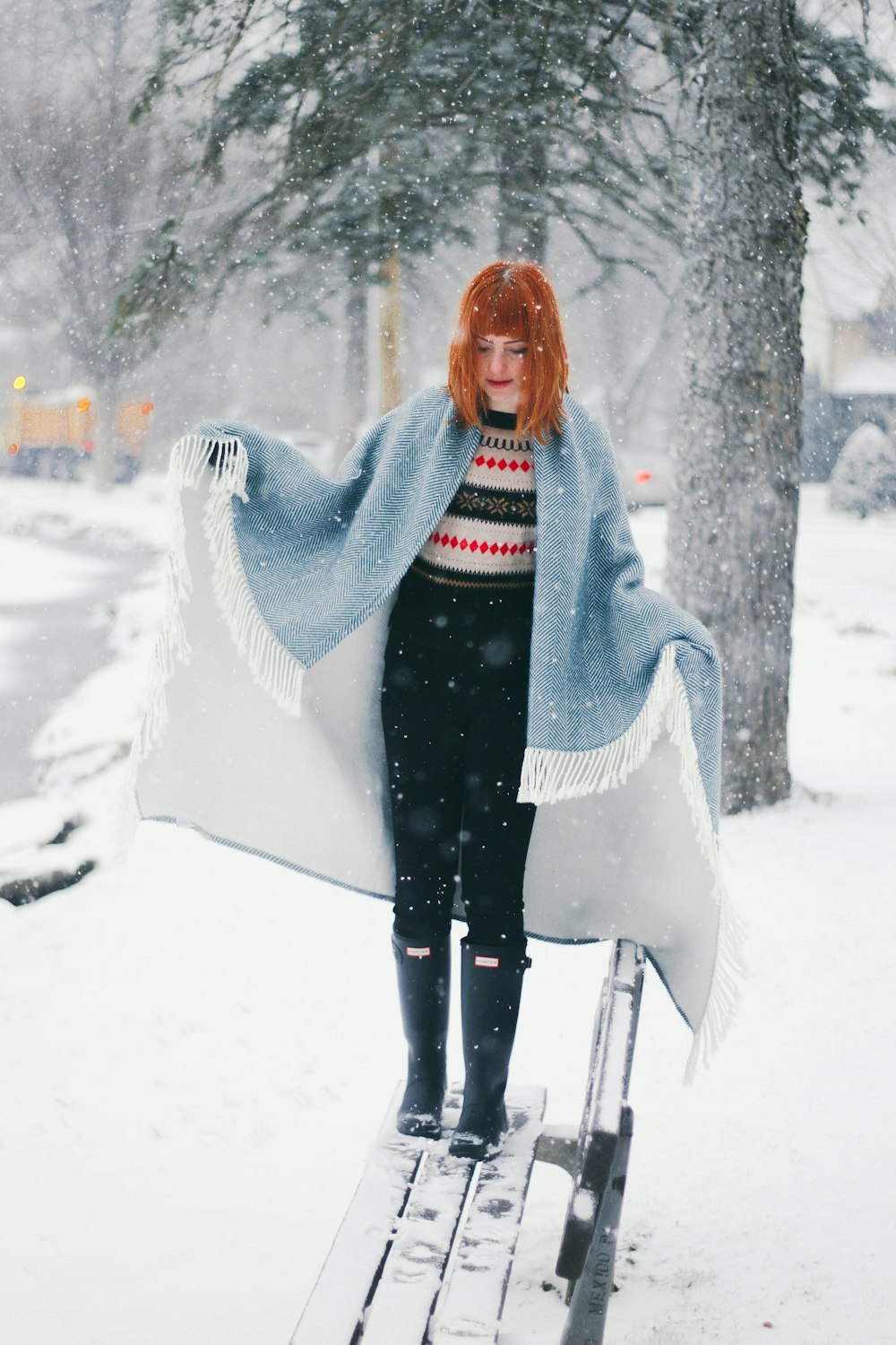 Frau steht auf schneebedeckter Bank, während sie tagsüber schneit