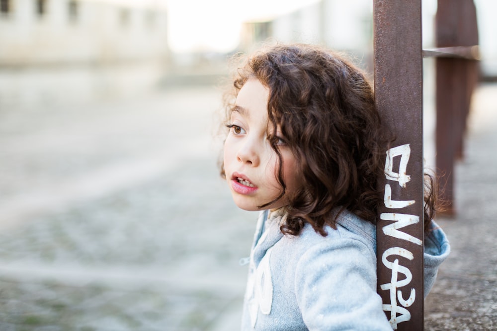 girl standing behind the brown stand during daytime