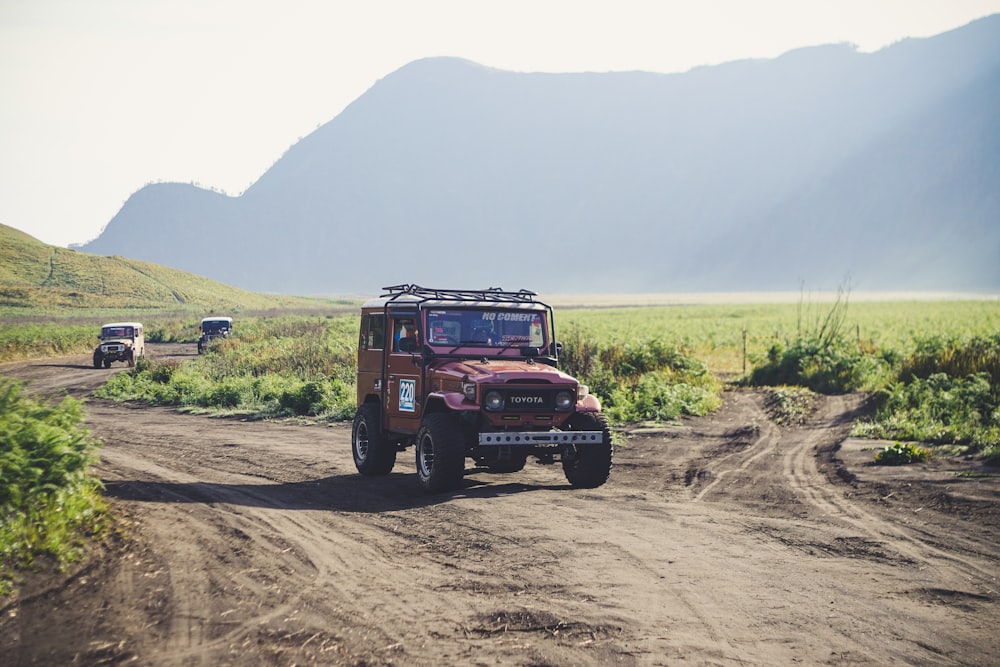 red off-road vehicle on pathway surrounded by grass during daytime