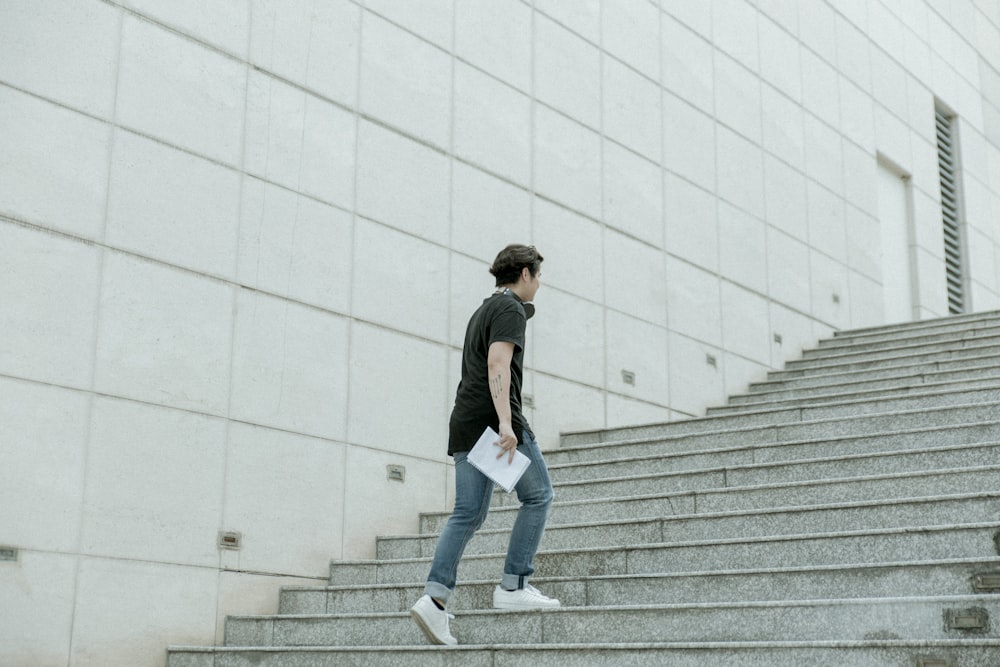 hombre sosteniendo papel de manta blanca caminando en una escalera gris