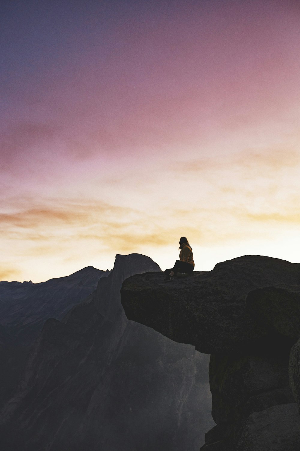 personne assise sur la falaise brune