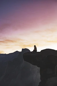 Woman sitting on a cliff path looking toward the horizon