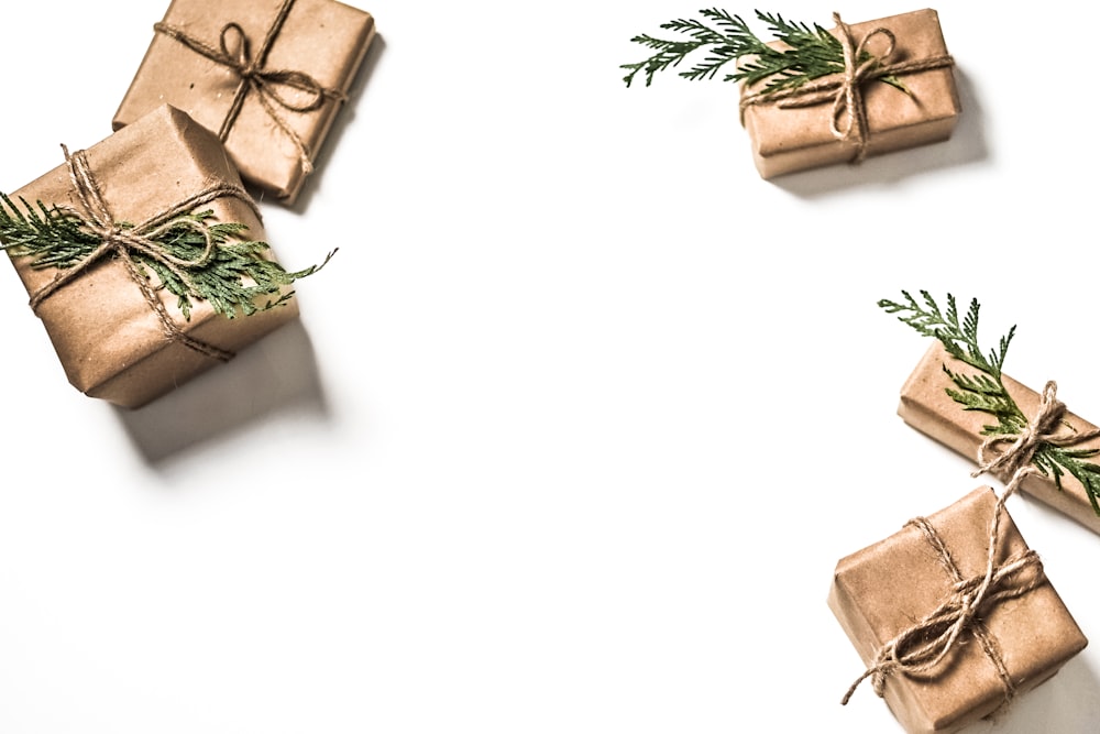 Quattro scatole regalo marroni su superficie bianca