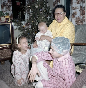 A cozy family scene with a mom and her three kids surrounded by toys, gadgets, and holiday decorations.