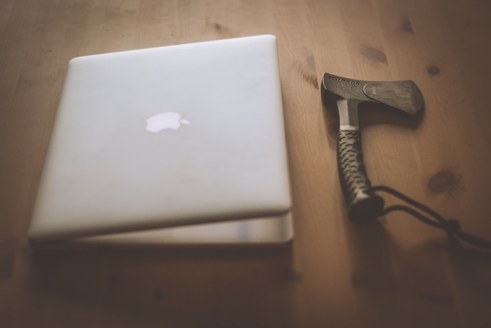 silver MacBook and black handheld tool