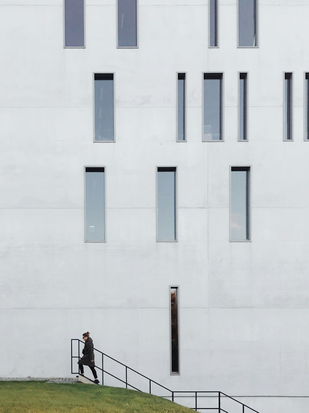 woman in red dress standing beside white concrete building during daytime