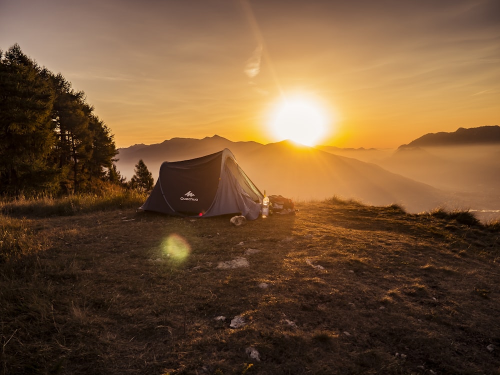 태양을 배경으로 한 산 꼭대기에 돔 텐트