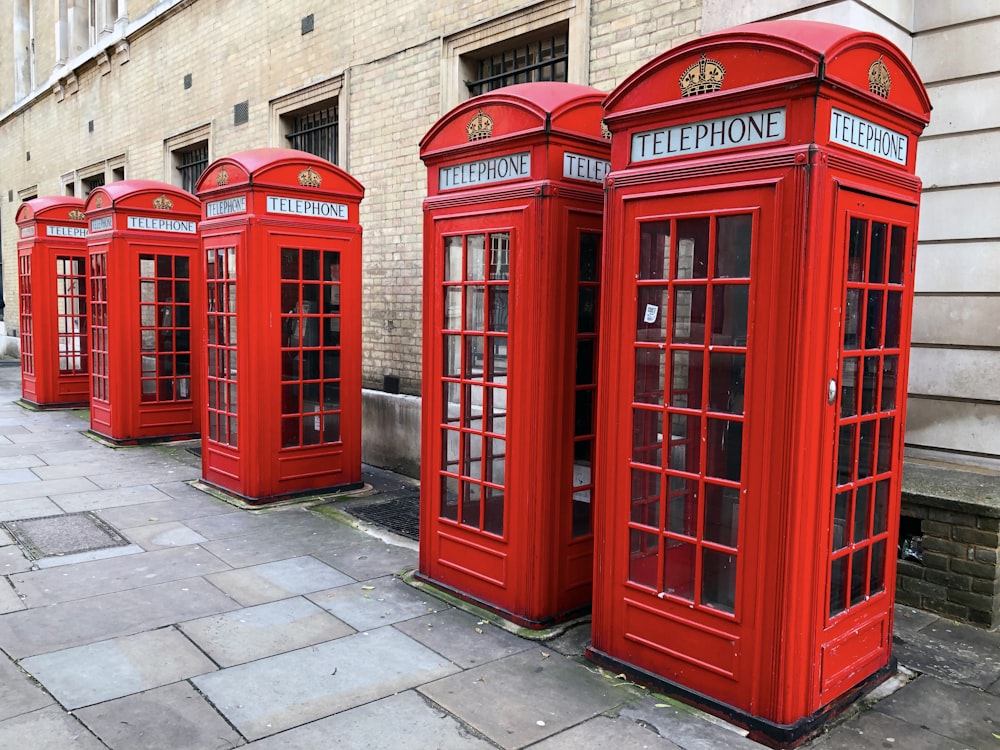 cabines telefônicas vermelhas alinhadas perto do prédio