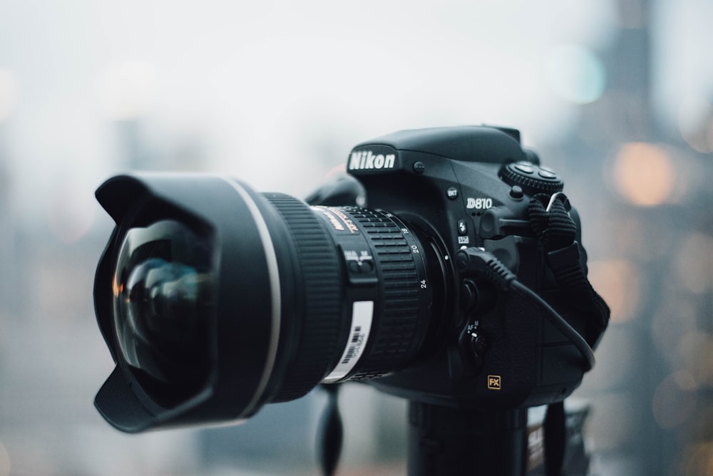 cámara Nikon D810 negra de pie sobre un trípode de metal negro durante el día