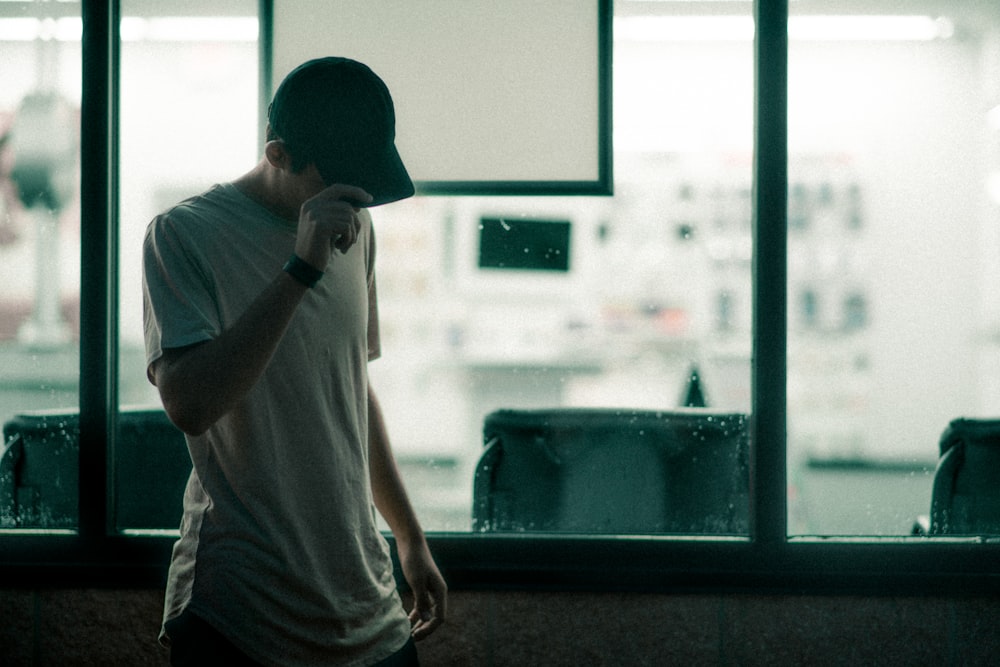 man in gray crew-neck t-shirt holding his cap