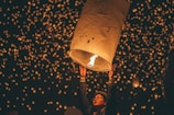 Moment frozen of the quinceañera releasing a group of white balloons into the night sky.