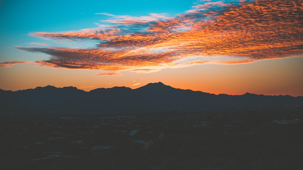 Silueta de la montaña bajo la foto del cielo nublado tomada durante la puesta del sol