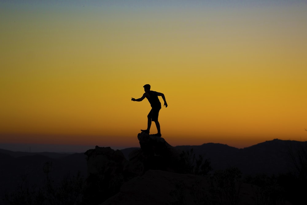 silhouette photo of person on mountain cliff