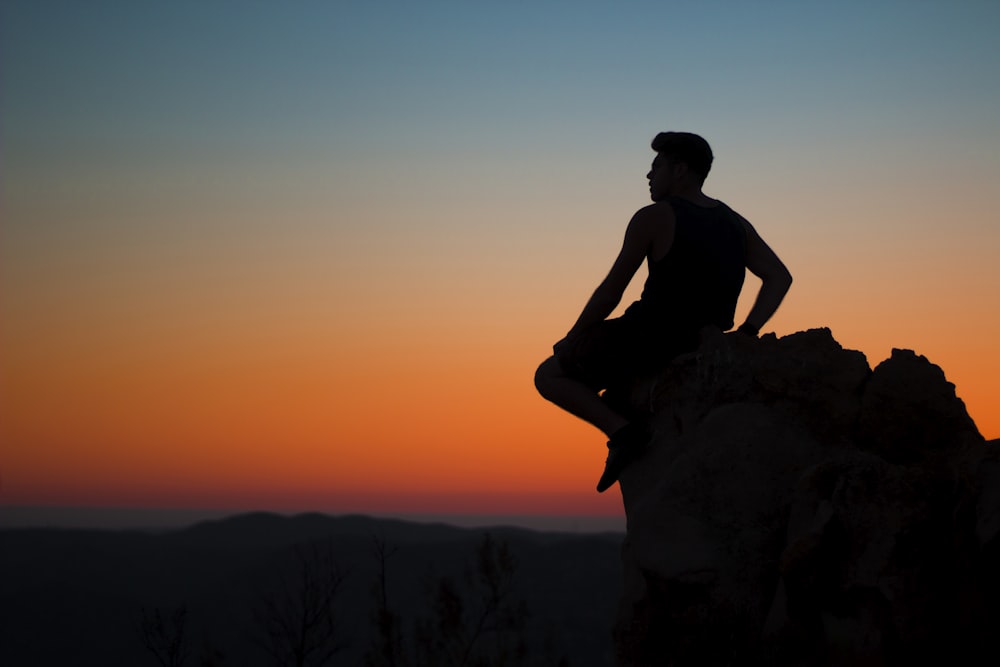 silhouette of man sitting at rocks