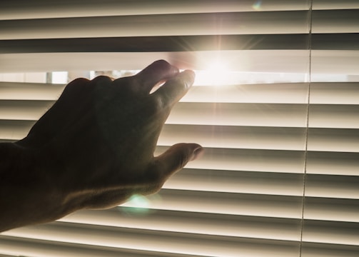 A close-up of a manual roller blind being adjusted in a bright living room.