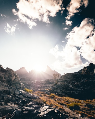 Sunlight breaking through clouds, casting light onto a rugged mountain landscape.