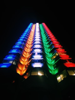 Night view of Binghatti Stars building illuminated with colorful lights.