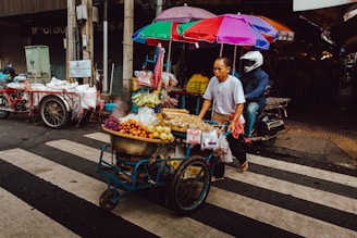 man pushing his food cart on pedestrian lane during daytime