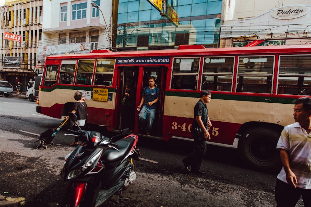 people walking down on red bus during daytime