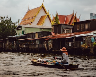 woman riding boat holding paddle on calm body of water in front of houses