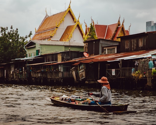 woman riding boat holding paddle on calm body of water in front of houses