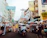 A colorful tuk tuk winding through a lively street filled with smiling tourists.