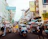 A colorful tuk tuk winding through a lively street filled with smiling tourists.