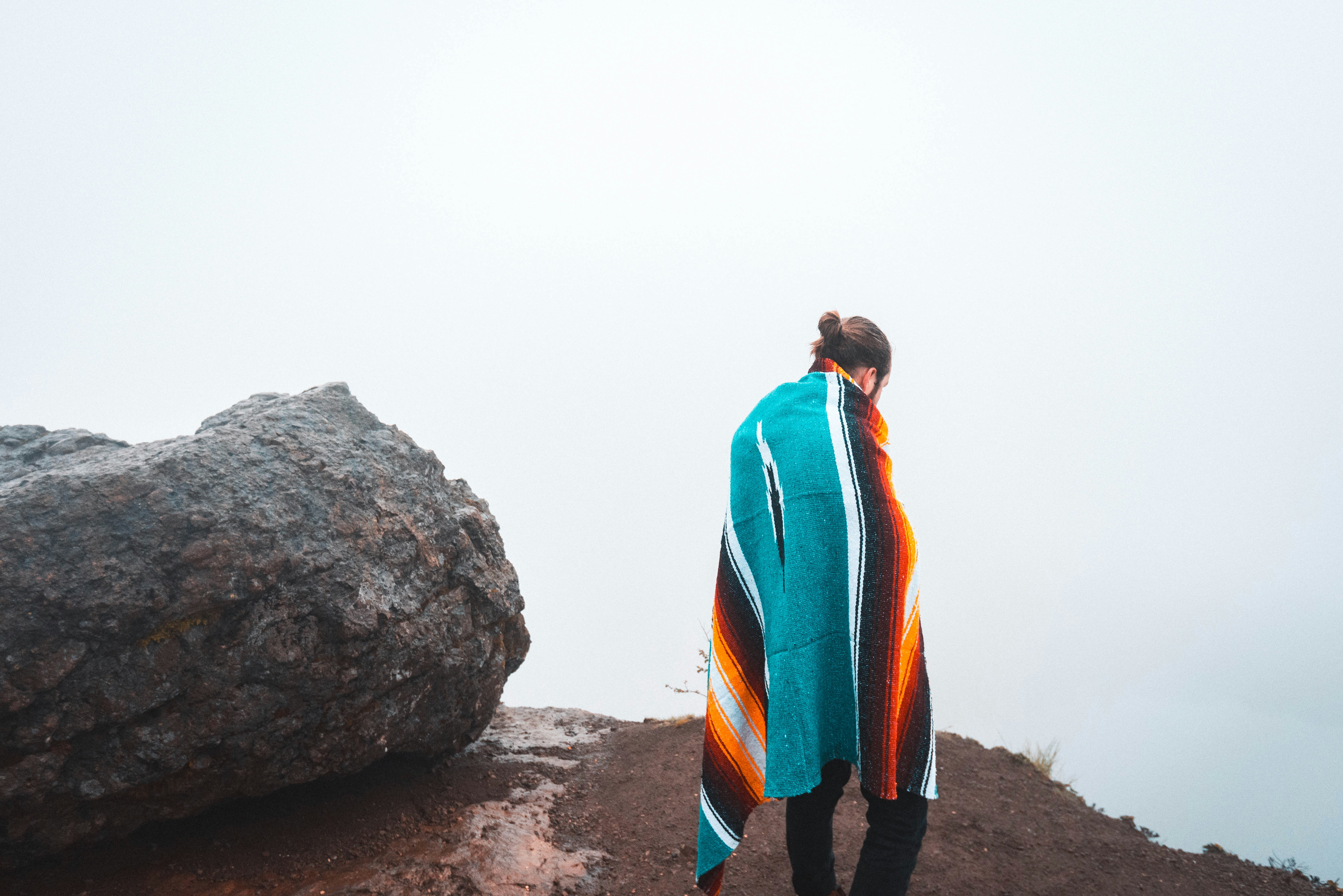 person standing beside black stone covering body of blanket, 