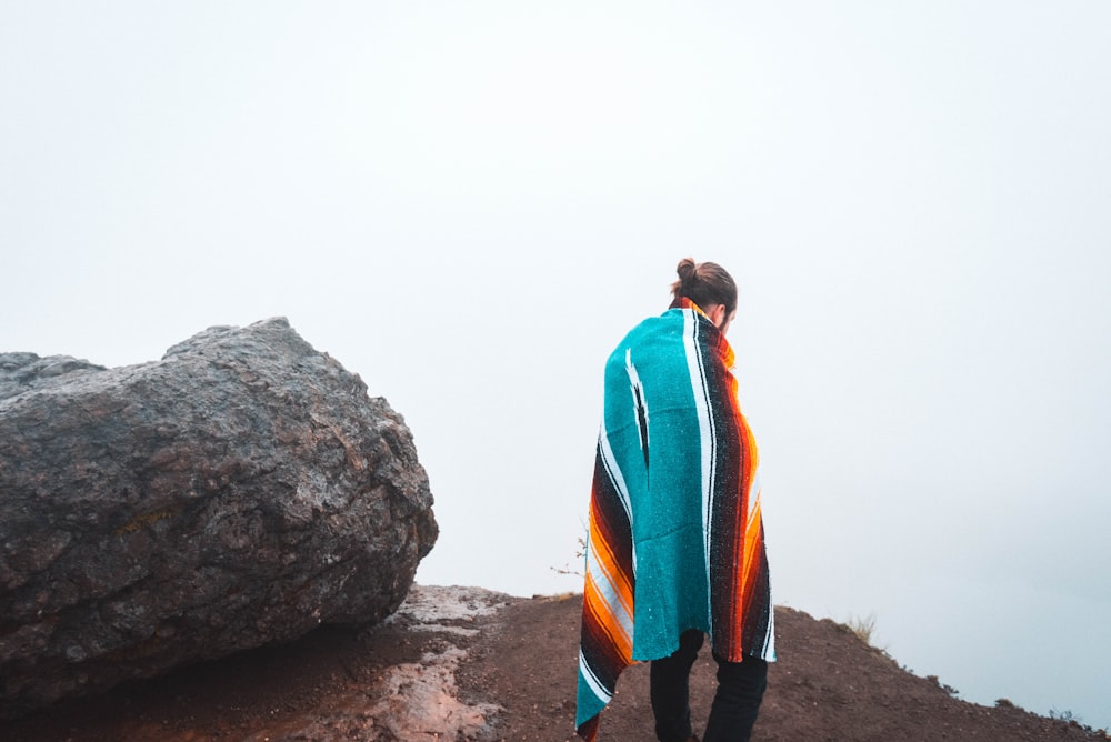 person standing beside black stone covering body of blanket