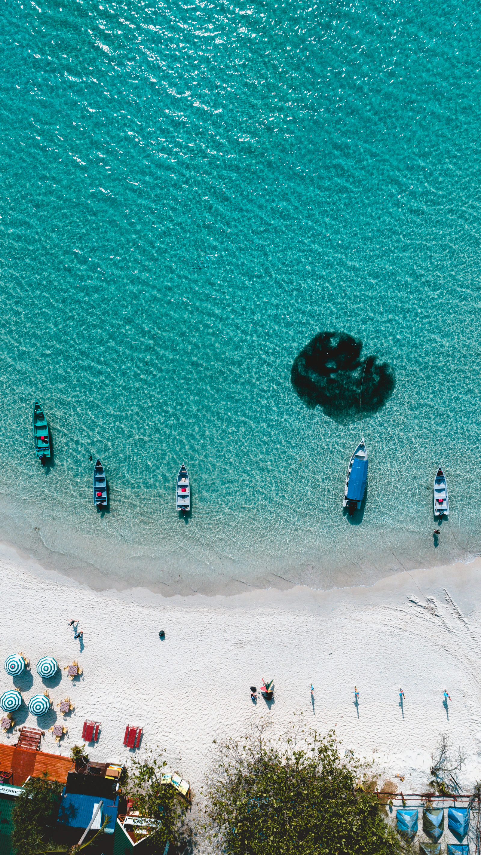 Vista cenital de una playa blanca de Perhentian con agua turquesa y pequeñas barcas