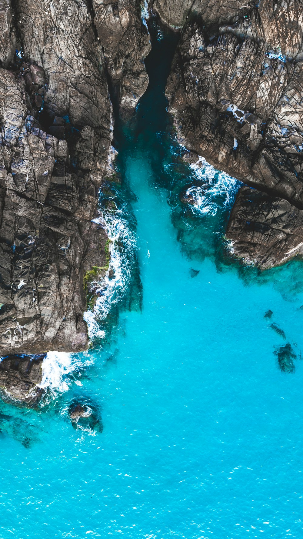 aerial photography of body of water beside cliff during day
