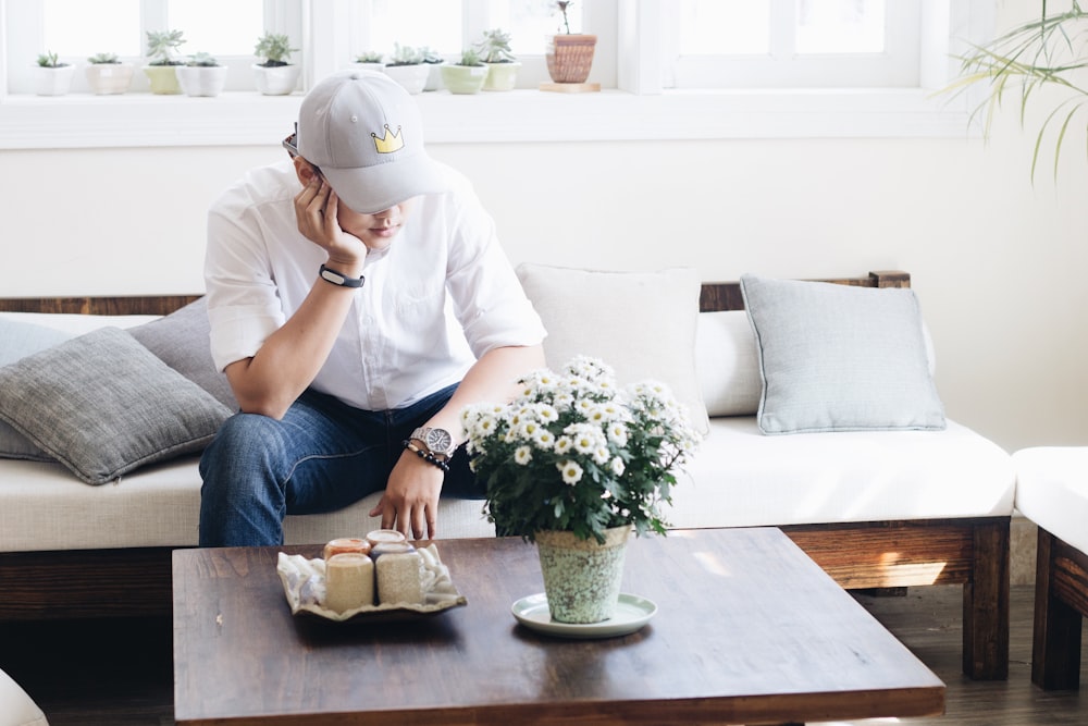 man sitting on white fabric sofa infront of coffee table inside the living room