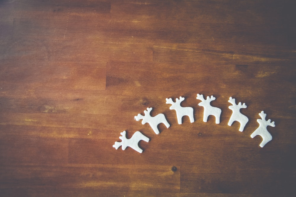 six white wooden deer decors on brown wooden surface