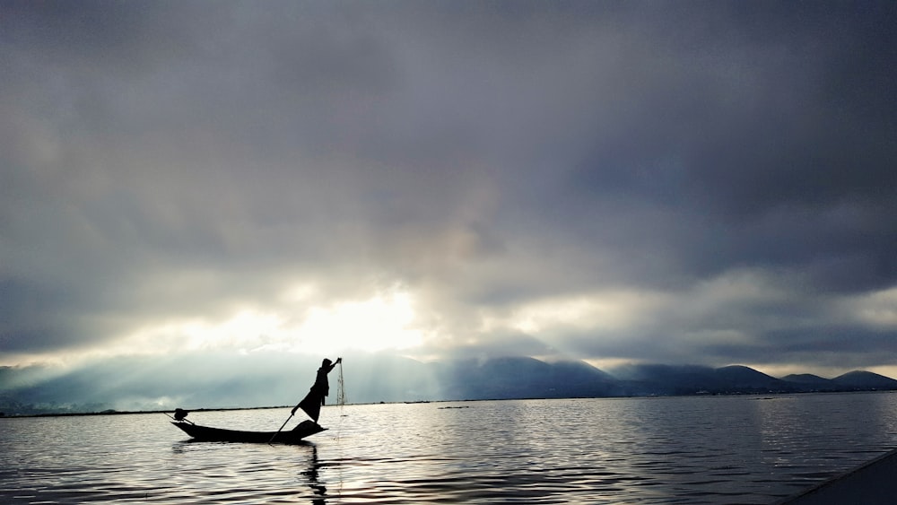 silhouette photo of person on boat during dawn