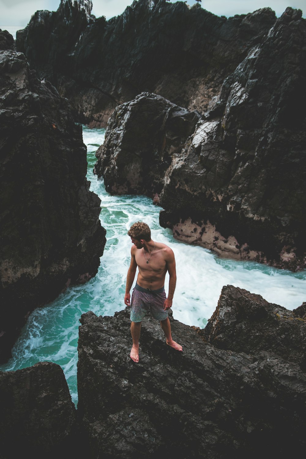 man standing on gray stone near cliff during daytime