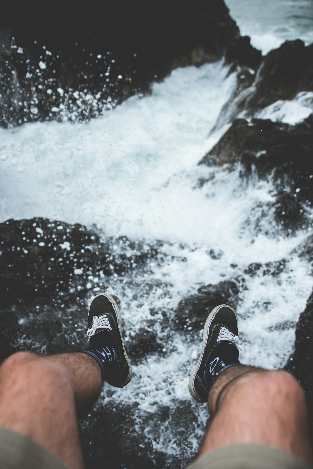 man sitting on rock near sea during daytime