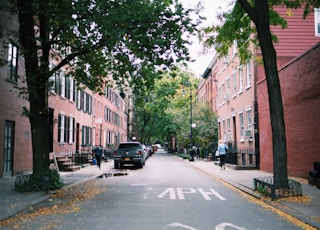 woman in blue top walking beside road and building during daytime