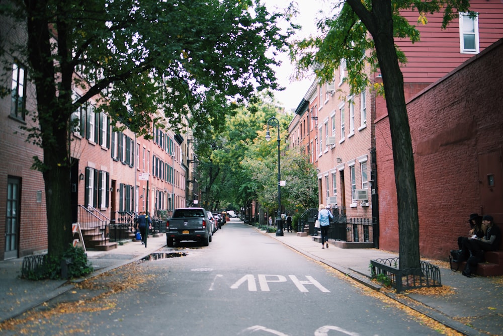 woman in blue top walking beside road and building during daytime