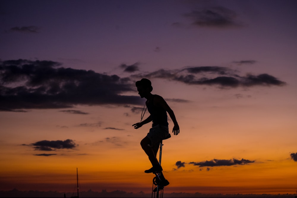 silhouette photo of man riding unicycle